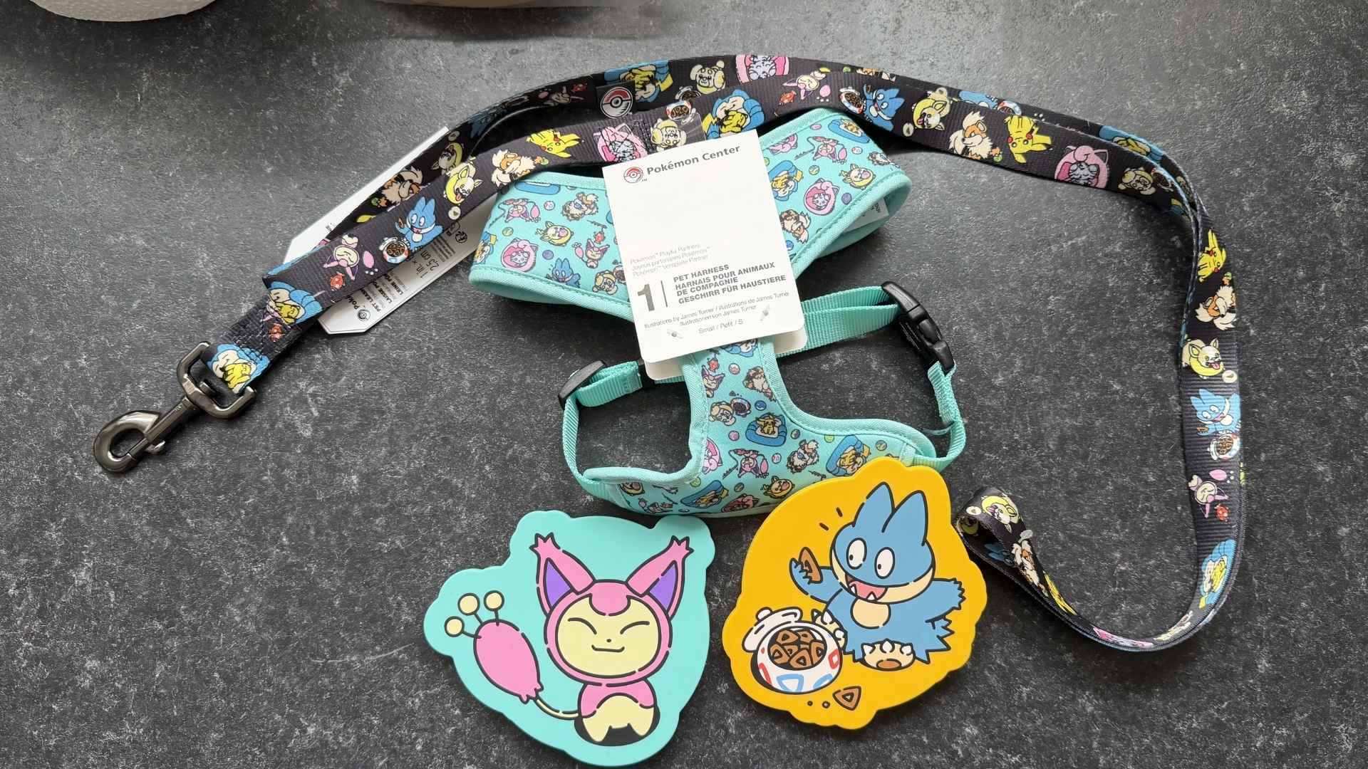 A set of Pokémon pet accessories, including a harness, a leash, and can covers on a marble countertop