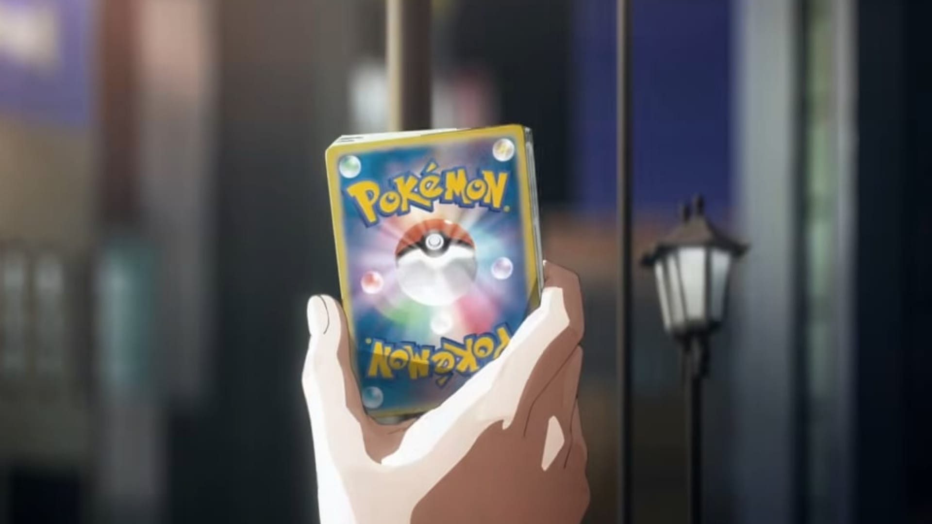 A hand holding up a Pokémon card from the upcoming Pokémon TCG movie